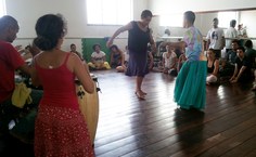 Claudia vai para o centro da roda ensinar o passo do jongo