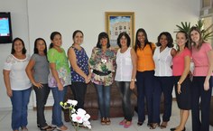 Colegas de trabalho reunidas em frente ao a quadro doado prla aposentanda de março