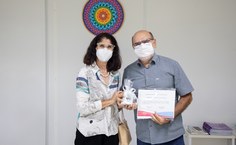 Professora Iracilda Moura, diretora do Instituto de Ciências Biológicas e da Saúde, entrega homenagem ao aposentado Sérgio Rocha