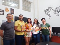 Professor supervisor Denis Rocha entregando os livros físico para os pibidianos junto com a professora Cirlene [de verde] (Arquivo Pessoal)