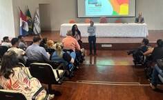 Professora Viviane Costa, diretora da Faculdade de Arquitetura e Urbanismo, Professor Anderson Dantas, diretor administrativo do HU, e professor Célio Rodrigues, sentado à mesa, na reunião de acolhimento