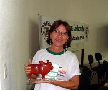 professora Edma Carvalho de Miranda, exibindo o prêmio