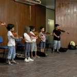 Crianças tocam violino na abertura da Semana de Educação Musical