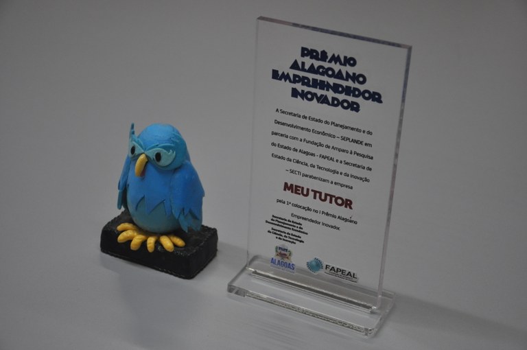 A corujinha azul é a mascote da empresa. Ao lado, placa do I Prêmio Alagoano Empreendedor Inovador