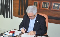 Reitor assinando as cópias do contrato
