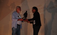 Tairone Feitosa (à esquerda) recebe a escultura O Homem da Capa Preta do artista Tadeu e seus bonecos