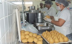 Funcionárias modelando coxinhas servidas como opção do cardápio à noite