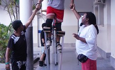 Nos primeiros momentos, estudantes recebem ajuda para caminhar com pernas de pau