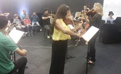 Lílian Pereira (à esq.) regendo a Camerata com o violino e acompanhando sua aluna Claudineide Pereira