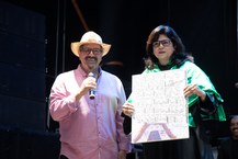 Fábio Pascola entrega à vice-reitora uma tela pintada por Hermeto