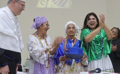 Mãe Mirian já com a Samarra, segura o capelo e o diploma recebido